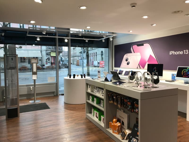 Electronics retail store with display screens, shelves of products, hardwood flooring.