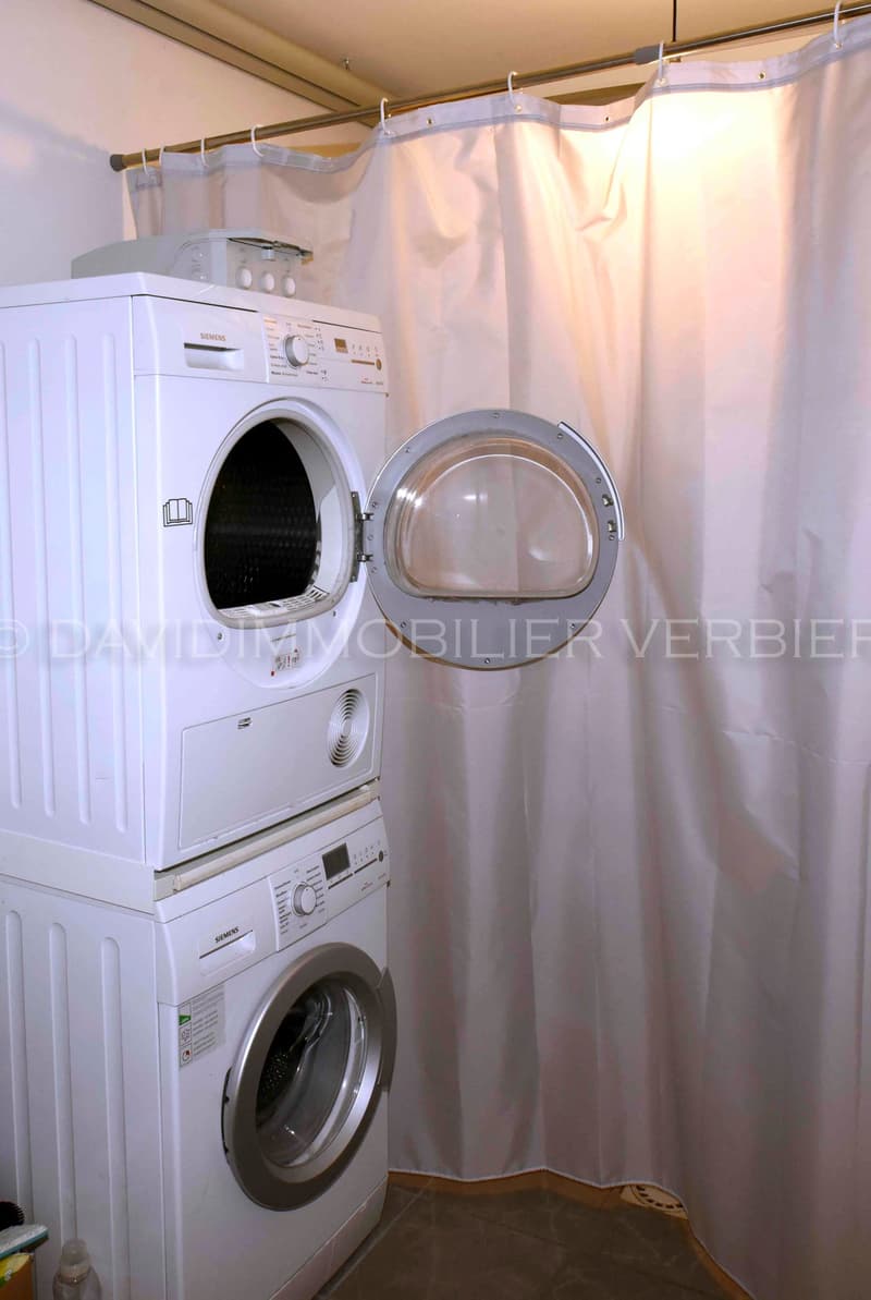 white stacked washer and dryer behind a curtain