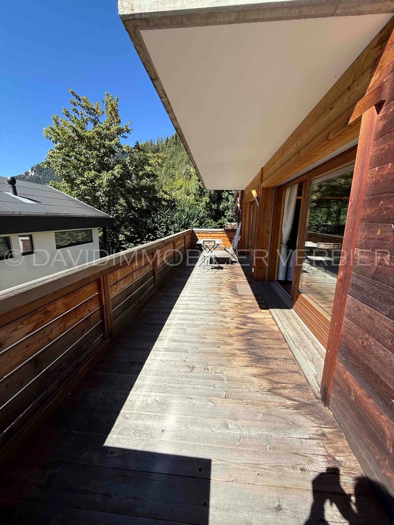 wooden deck, wooden fence, table, chairs, sliding glass door, trees, building, mountains, clear blue sky