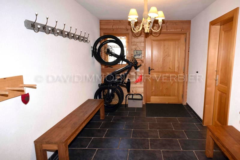 wooden bench, bicycle mounted on wall, wooden doors, tiled floor, chandelier