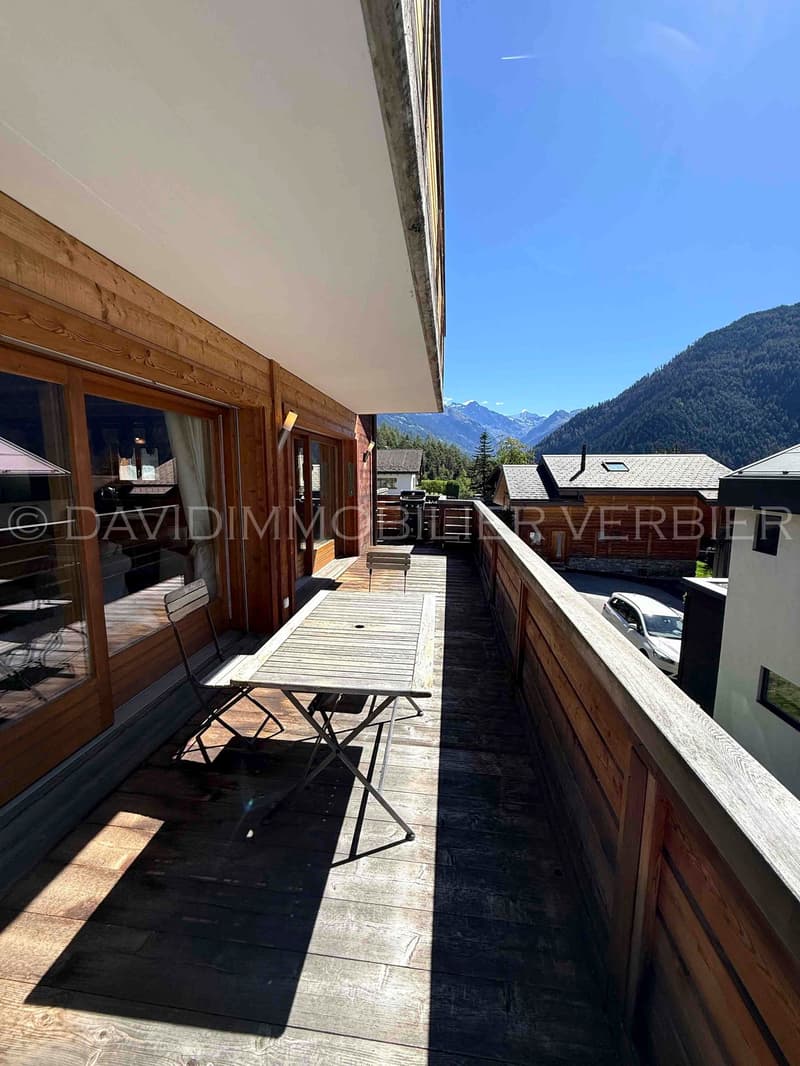 Mountainside house, wooden exterior, large balcony, wooden deck, outdoor dining table and chairs, mountain view