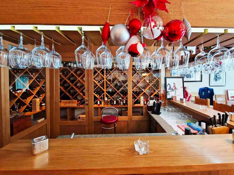 wooden counter, wooden cabinets, wine bottles, wine glasses, bar stools, wooden tables, picture frames, Christmas ornaments