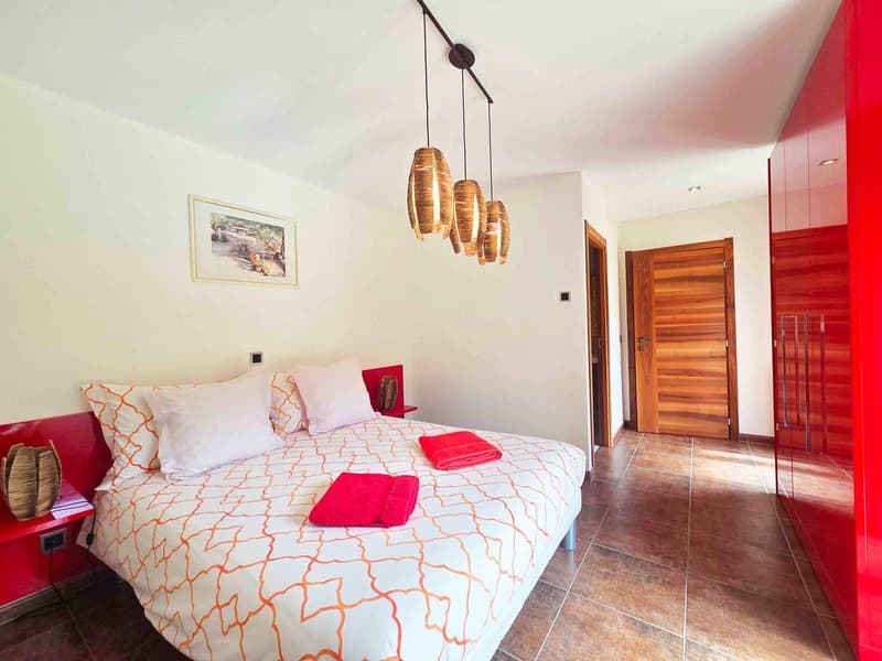large bed, red towels, red furniture, wooden flooring, wooden door, hanging lamps