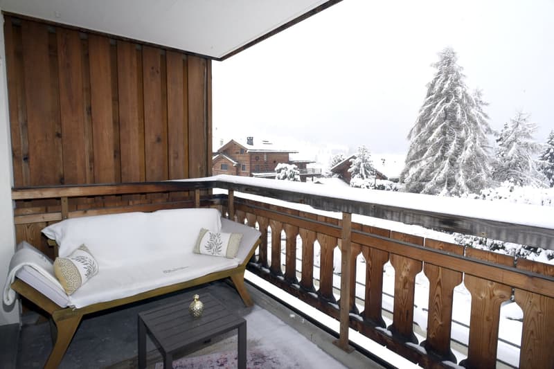 wooden balcony, snowy landscape, white couch, small table, wooden railing
