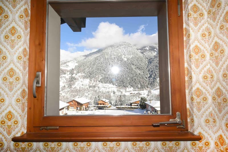 A wooden window frame showing a snowy mountain view