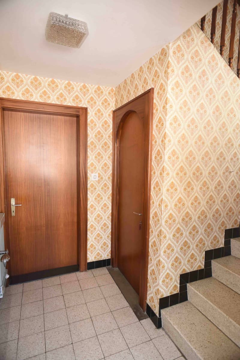 tiled floor, wooden doors, decorative wallpaper, stairs, light fixture, radiator