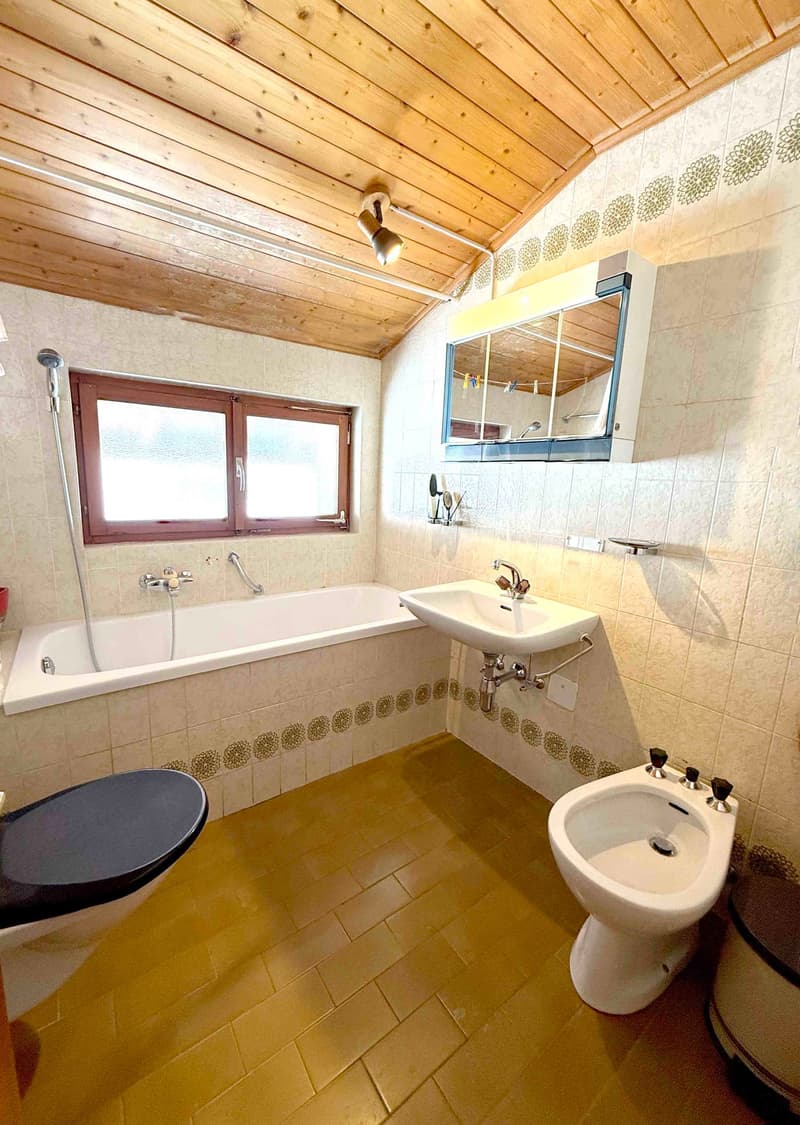 Bathtub, sink, mirror, toilet, wooden ceiling, white tiles, window