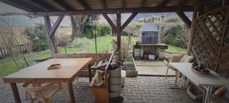 Vue du jardin et du barbecue depuis la terrasse couverte