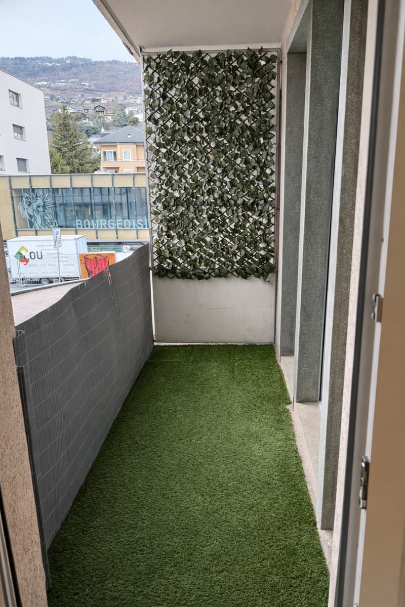 balcony, gray railing, green turf, building wall, glass door