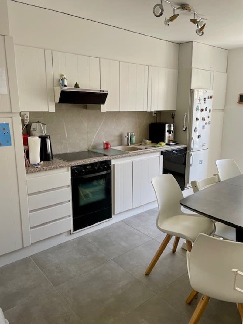 a modern kitchen with white cabinetry, stainless steel appliances, tile flooring, a gray dining table, and white chairs