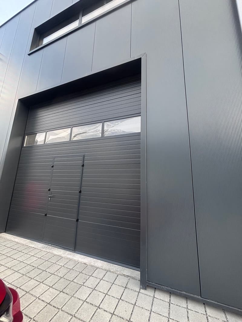 Exterior wall with a double garage door and a side pedestrian door, brick floor