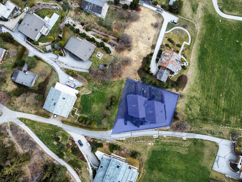 House: grey roof, blue structure, green surroundings, visible driveway, car parked outside