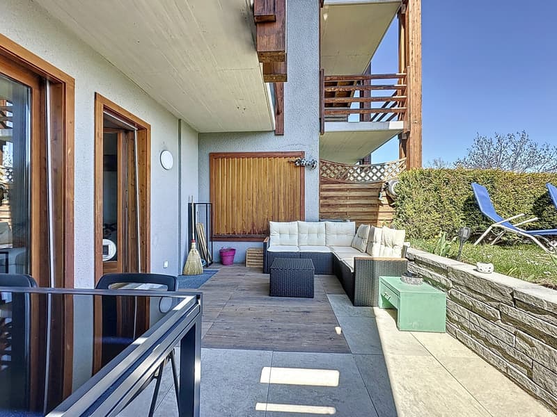 2-story house with wooden balcony, garage, outdoor seating area with rattan furniture, and landscaped garden