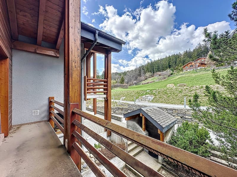 balcony with wooden railing, exterior wall, beautiful mountain view, distant building