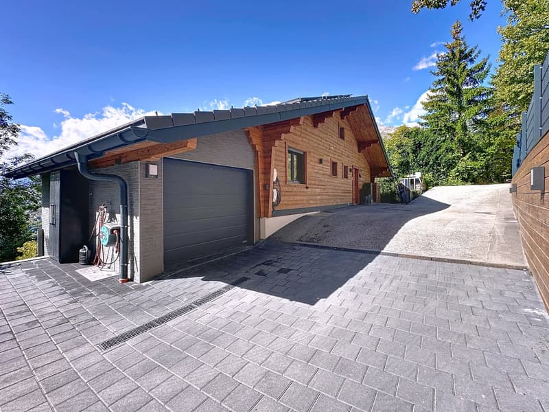 two-story house, wooden and brick wall, attached garage, paved driveway, green landscape