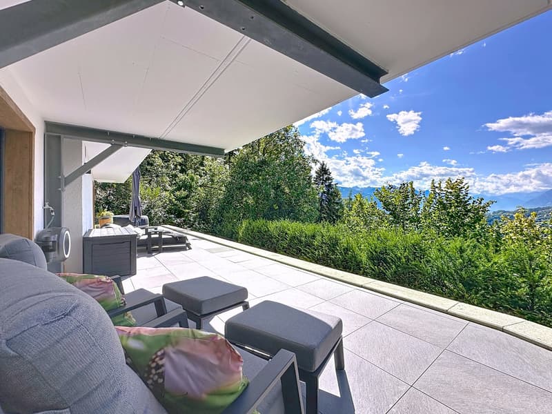 covered terrace with lounge chair, cushions, tables, greenery and mountains view