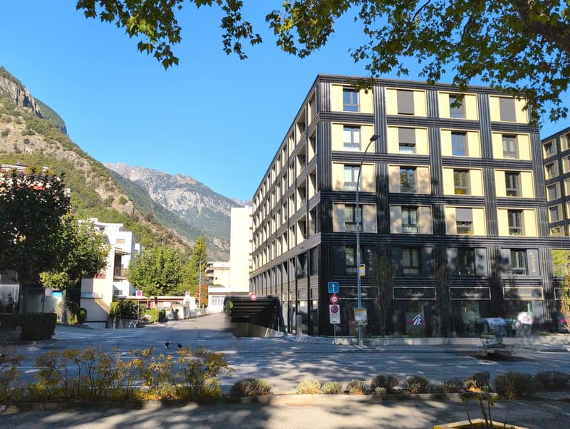 Building with multiple floors, modern architecture, raised ground floor, and surrounded by trees and bushes