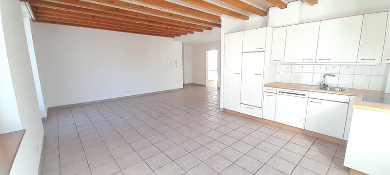 Empty kitchen with wooden ceiling, white tile floor, white kitchen cabinets, wooden countertops, stainless steel sink, and stainless steel dishwasher.
