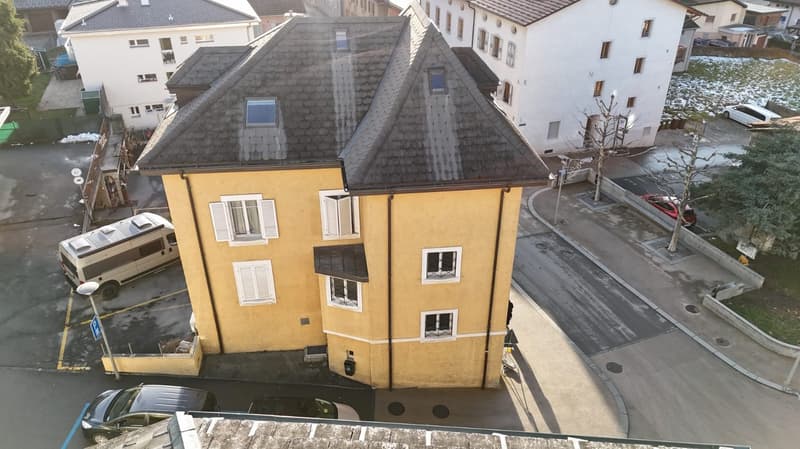 Apartment building, yellow exterior, 3 floors, balcony on 2nd floor, car parking spaces, snow-covered area in the distance