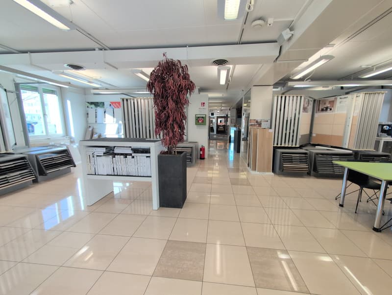 tiled floors, office desks with materials, potted plants, lights on ceiling, open corridor