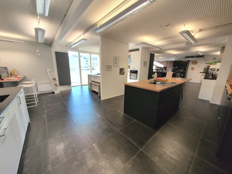 Open kitchen concept, modern and spacious with gray tiled floor, island countertop, sleek cabinetry, and ample natural light from windows.