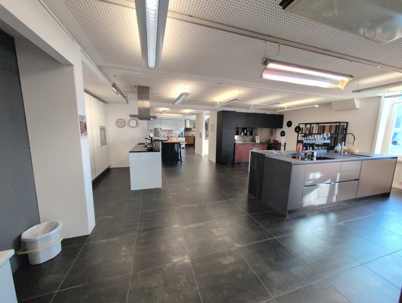 modern open kitchen, white cabinets, island countertop, black tiles, bright lighting, built-in dishwasher, washing machine
