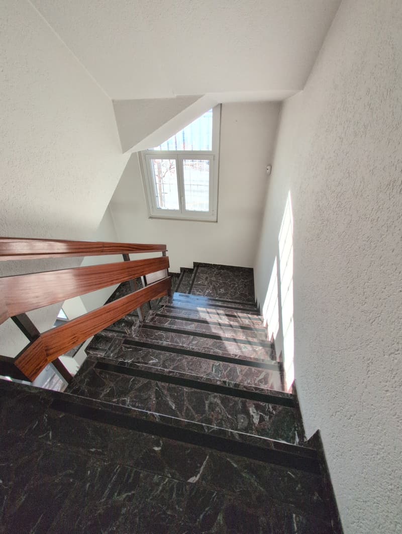 wooden handrail, marble steps, white painted walls, window at top