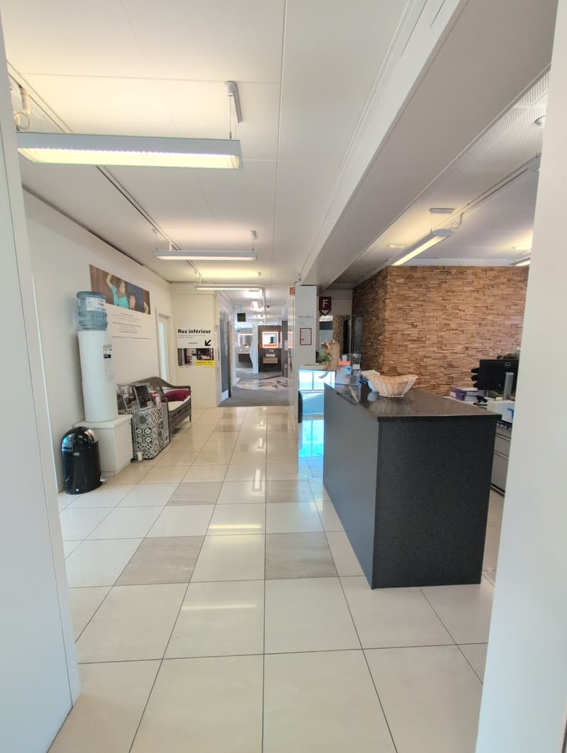 modern hallway with white tile floor, modern lighting, reception desk, chairs, water dispenser, open space