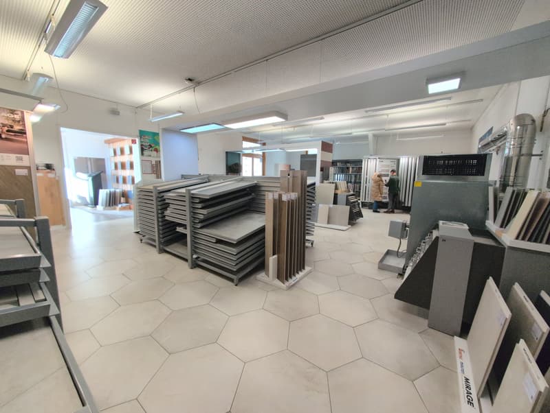 A store with white hexagonal tiles on the floor, metal racks, and shelves with grey storage boxes.