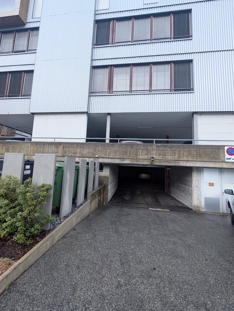 concrete building, 4 floors, metal railing, parking garage, dumpsters