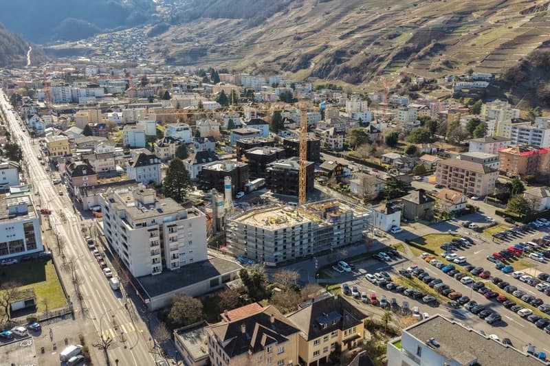City overview with construction site, mountains, and parking lots.