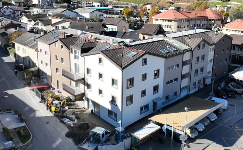 5 story building, white walls, brown roof, multiple windows, balconies, a car park, a hotel building, cars parked in front