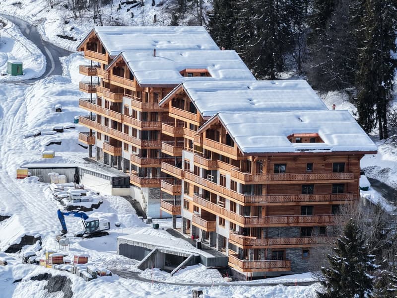 large ski lodge with wooden balconies, covered in snow, located on a mountainside