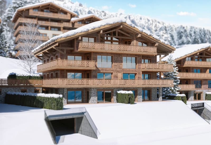 A multi-story chalet with wooden balconies, large windows, surrounded by snow, and a clear view of the mountain range in the background.