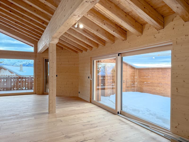 Wooden room, wooden floor, sliding glass doors, wooden beams, snowy landscape outside