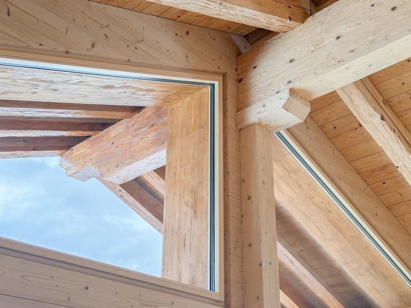 Exposed wooden beams, glass windows, sloped roof, wooden floor