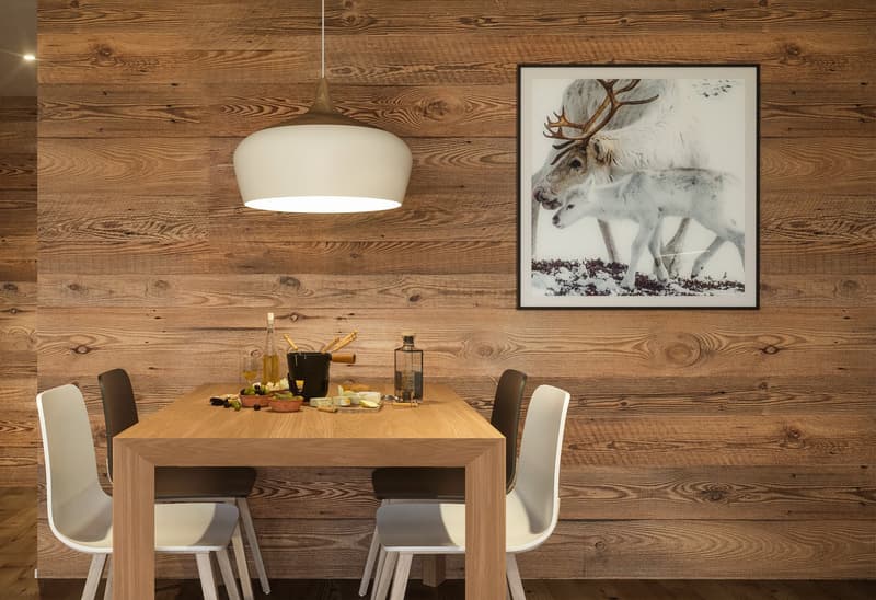 Dining table, four chairs, wooden wall, painting of reindeer, hanging lamp