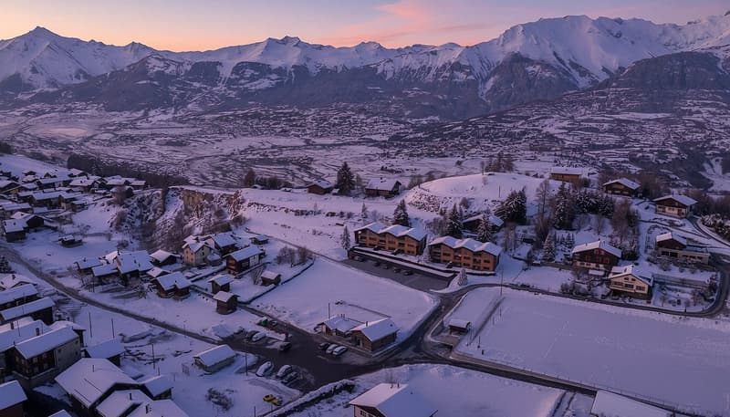 Mountains, snow, buildings, roads, cars, and trees