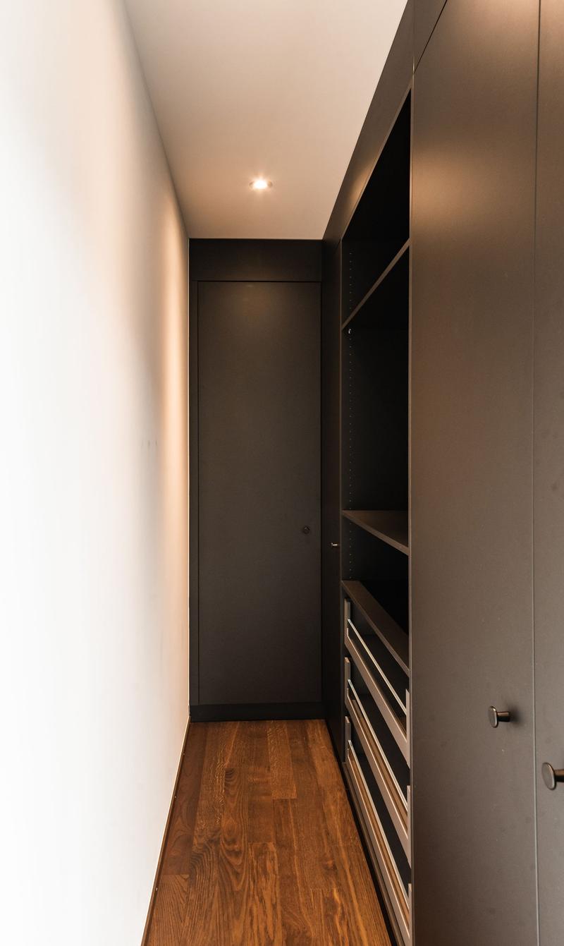 wooden floor, white wall, black wardrobe, shelves, drawers