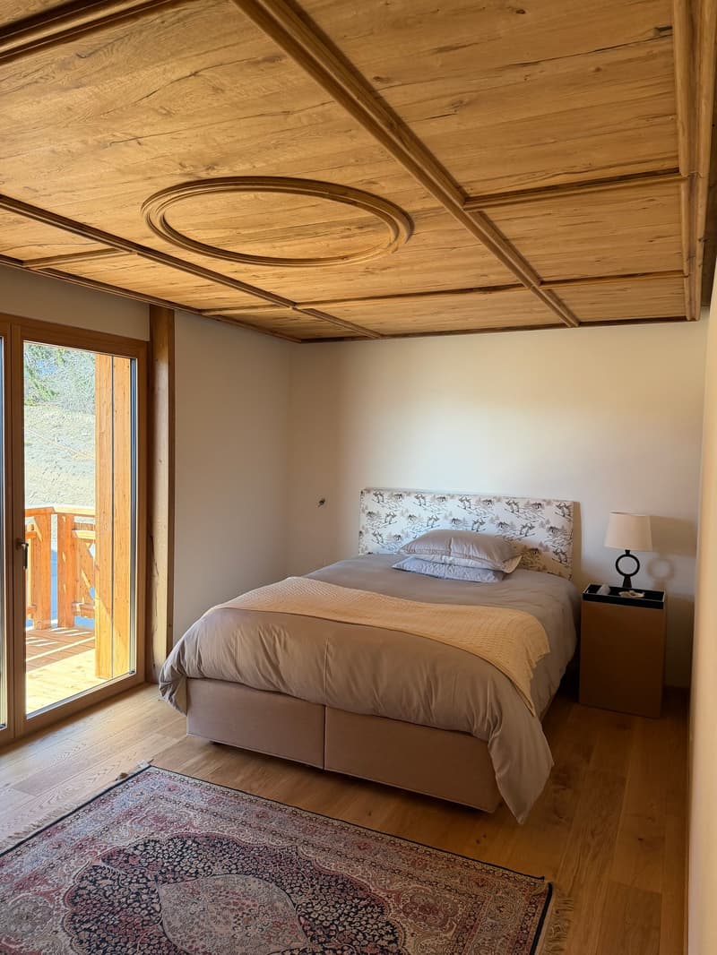 bedroom with wooden ceiling, bed, nightstand, lamp, rug, glass door, balcony