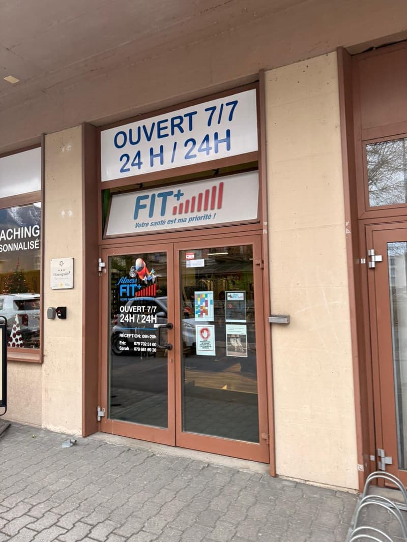 Entrance to a fitness center, double glass doors, brown wooden frame, sign above the door, open 24/7