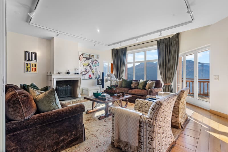 a living room with a large window, a couch, chairs, and a fireplace