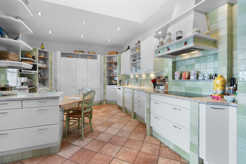 une grande cuisine avec des armoires blanches et des chaises vertes / a large kitchen with white cabinets and green chairs