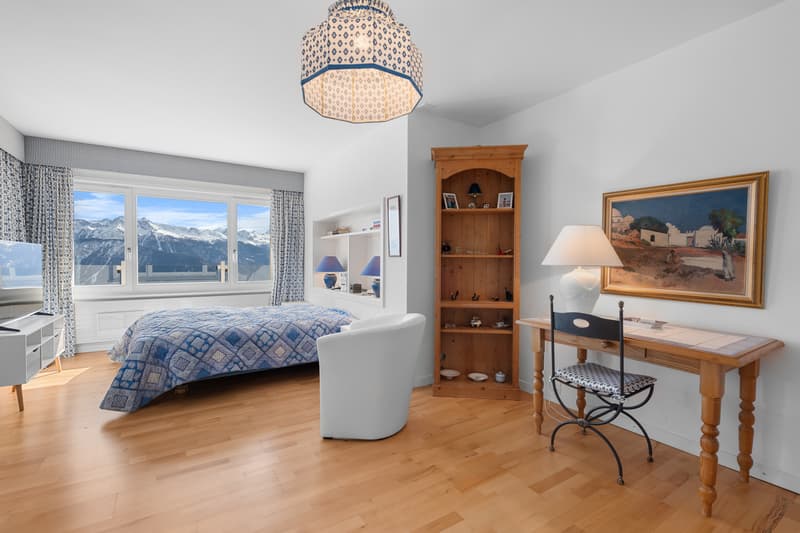 une chambre avec du parquet, une grande fenêtre, un lit et un bureau / a bedroom with wood floors, a large window, a bed, and a desk