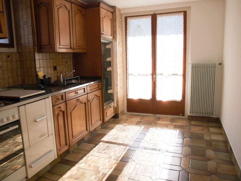 kitchen with wooden cabinets, tiled floor, double doors, window with curtains, white oven, gas stove, sink, faucet, radiator