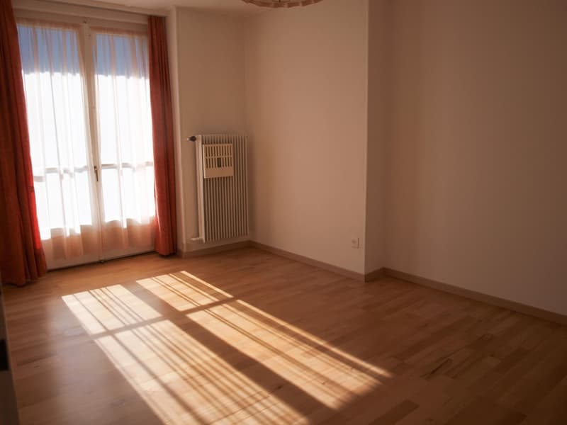 empty room, wooden floor, white walls, large window with white curtains, white radiator