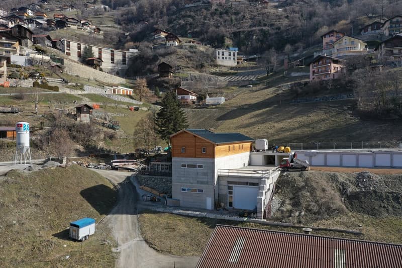 House under construction, brown and white exterior, garage, under construction, several buildings visible in the background