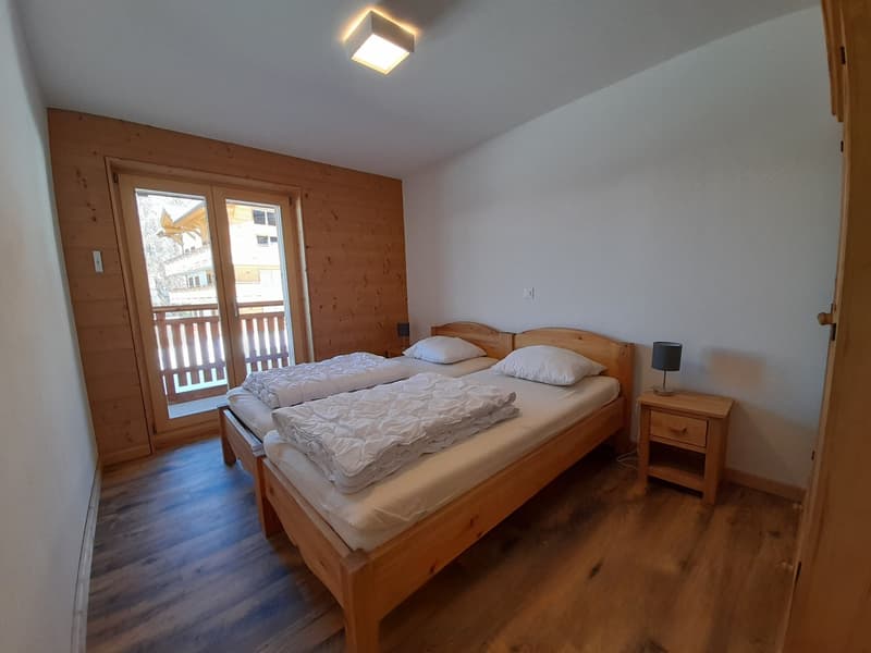bedroom with two twin beds, wooden walls, glass balcony doors, white bedding