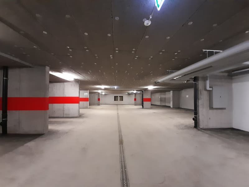 empty parking lot, concrete pillars, red stripes, lamps on ceiling