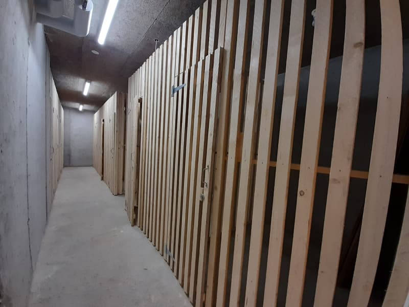 A concrete hallway lined with wooden storage cabinets